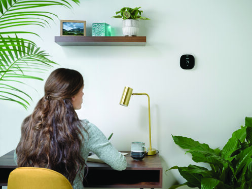 Young woman checking the thermostat setting while she works from home.