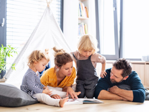 Mom and Dad reading to their kids in their cool air conditioned home