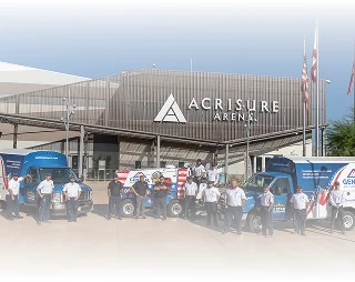Service team standing in front of branded trucks outside Acrisure Arena.