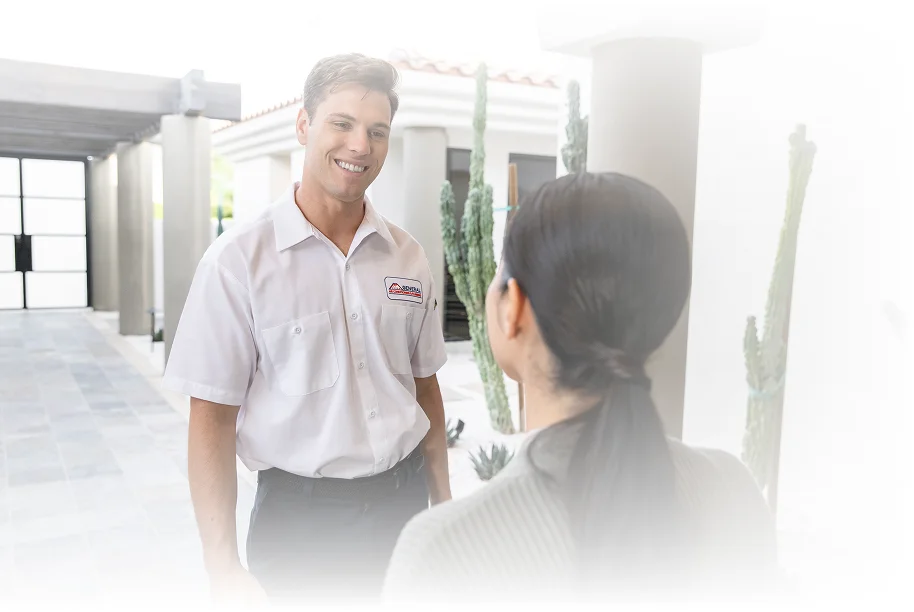 Technician speaking with a homeowner at the front entry of a house.